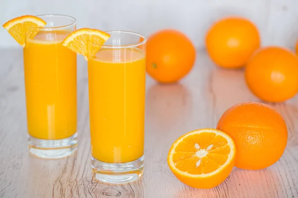 Orangensaft in Gläsern vor hellem Holzhintergrund — Stockfoto