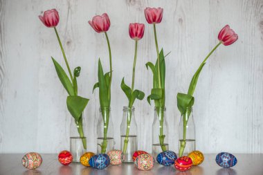 Paskalya Paskalya yumurtaları ve açık ahşap renkli cam şişelerde Pembe Lale arka plan