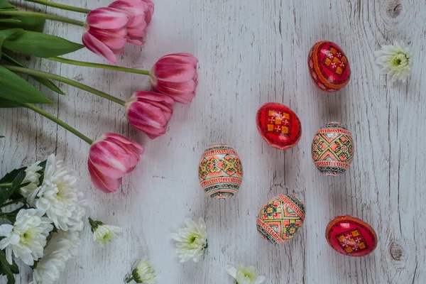 Sfondo pasquale con uova di Pasqua e tulipani rosa su sfondo di legno chiaro — Foto Stock