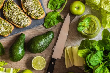 Detoks diyet. Yeşil smoothie ve avokado ile sanwiches. Ahşap arka plan üzerinde farklı sebze
