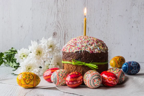 Easter cake kulich with eggs and spring flowers on light wooden background — Stock Photo, Image