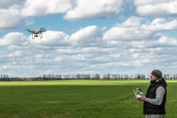 Mann bedient fliegenden Drohnen-Quadrocopter auf der grünen Wiese — Stockfoto