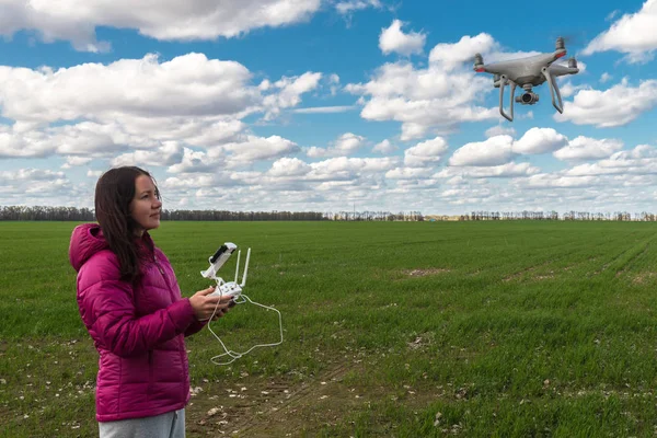 girl operating of flying drone quadrocopter at the green field