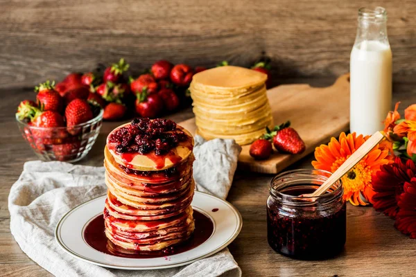 Stapel hausgemachter amerikanischer Pfannkuchen mit Marmelade und Erdbeeren auf hölzernem Hintergrund — Stockfoto