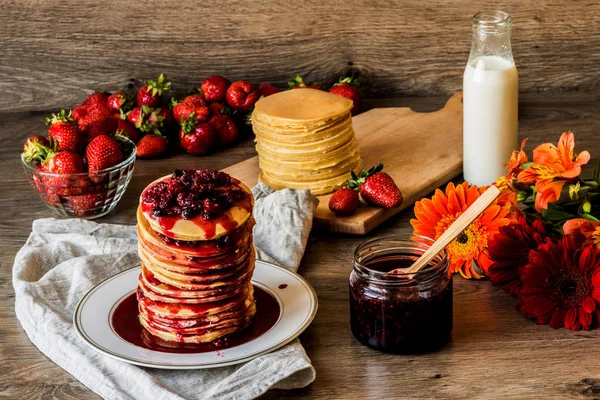 Stapel hausgemachter amerikanischer Pfannkuchen mit Marmelade und Erdbeeren auf hölzernem Hintergrund — Stockfoto