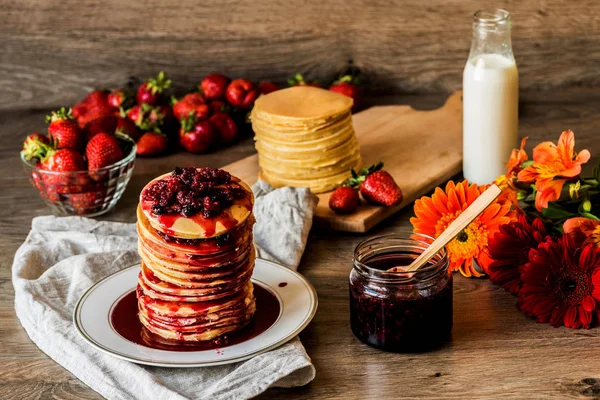 Stapel hausgemachter amerikanischer Pfannkuchen mit Marmelade und Erdbeeren auf hölzernem Hintergrund — Stockfoto