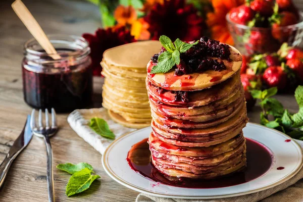 Stack of homemade american pancakes served with jam and strawberries on wooden background — Stock Photo, Image