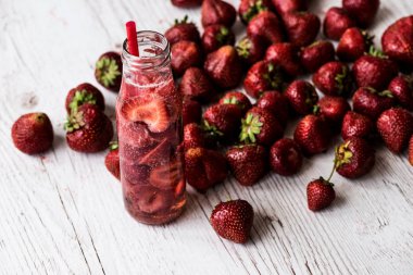 Beyaz ahşap zemin üzerinde çilek ile şişe suda Detoks