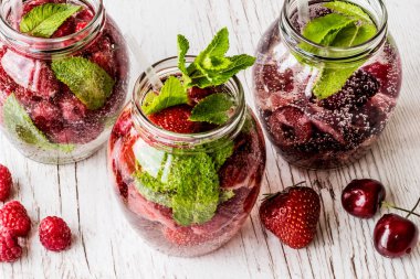 Ahududu, çilek, kiraz Beyaz ahşap zemin üzerine suyla detoks. Sağlıklı içecekler