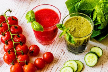 Taze domates suyu ve Yeşil yüzlü beyaz ahşap zemin üzerinde iki bardaklarda Detoks