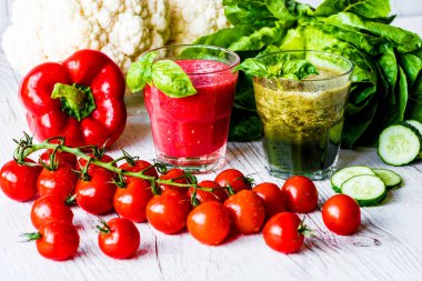 Taze domates suyu ve Yeşil yüzlü beyaz ahşap zemin üzerinde iki bardaklarda Detoks