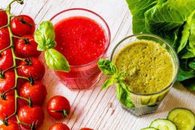 Taze domates suyu ve Yeşil yüzlü beyaz ahşap zemin üzerinde iki bardaklarda detoks. Yakın çekim.