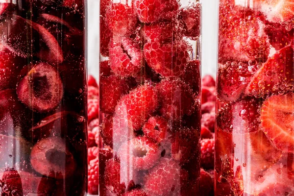 Макро снимают детоксикационную воду в трех бутылках с ягодами. макро — стоковое фото
