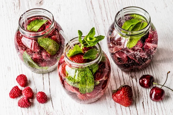 Ahududu, çilek, kiraz Beyaz ahşap zemin üzerine suyla detoks. Sağlıklı içecekler