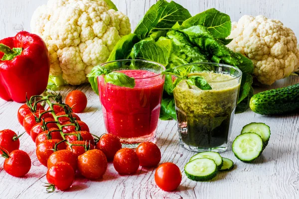 Taze domates suyu ve Yeşil yüzlü beyaz ahşap zemin üzerinde iki bardaklarda Detoks