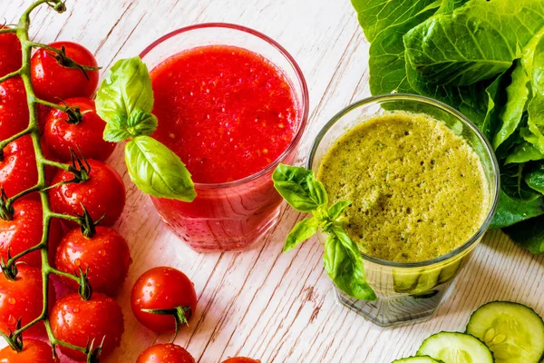 Taze domates suyu ve Yeşil yüzlü beyaz ahşap zemin üzerinde iki bardaklarda detoks. Yakın çekim.