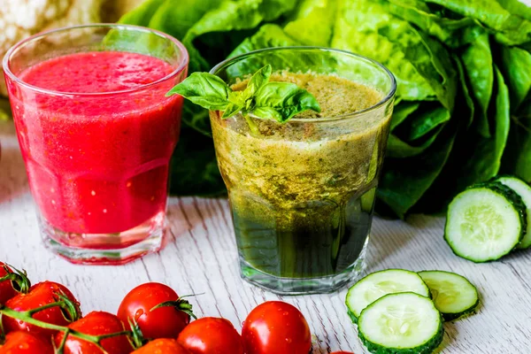 Taze domates suyu ve Yeşil yüzlü beyaz ahşap zemin üzerinde iki bardaklarda detoks. Yakın çekim.