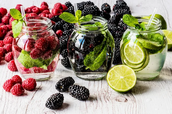 Tre typer av detox vatten med björnbär, jordgubb, lime med ingredienser på vit trä bakgrund — Stockfoto