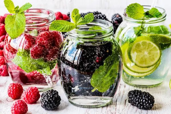 Beyaz ahşap zemin üzerinde malzemelerle Detoks su ile böğürtlen, çilek, üç tür kireç