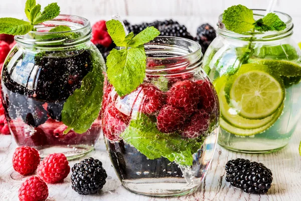 Beyaz ahşap zemin üzerinde malzemelerle Detoks su ile böğürtlen, çilek, üç tür kireç