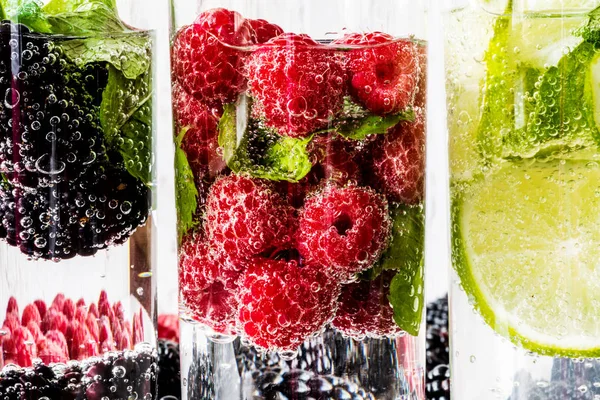 Tre tipi di acqua disintossicante con mora, fragola, lime con ingredienti su fondo bianco in legno. Super macro — Foto Stock