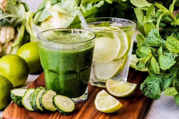 Zelené smoothie a detoxikační voda s limetkou, máta a ledu na dřevěné pozadí. detoxikační dietu. Detail — Stock fotografie