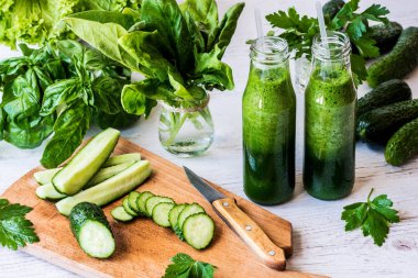 Detoks diyet. Hafif ahşap arka plan üzerinde malzemelerle taze yeşil smoothies iki küçük şişe.