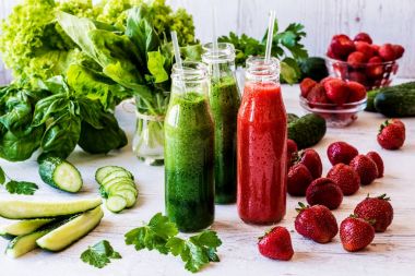 Taze yeşil smoothies ve hafif ahşap arka plan üzerinde malzemelerle çilek güler yüzlü. Sağlıklı Detoks içecekler.