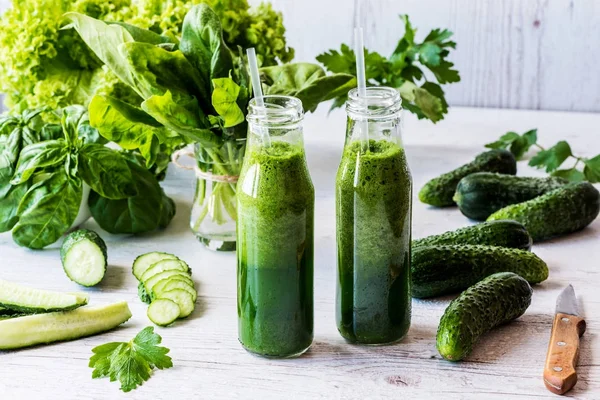 Detoks diyet. Hafif ahşap arka plan üzerinde malzemelerle taze yeşil smoothies iki küçük şişe.