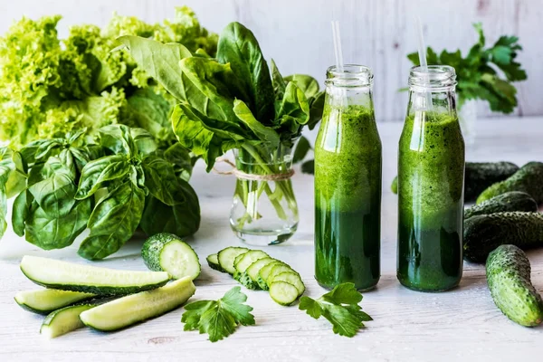 Dieta de desintoxicación. Dos pequeñas botellas de batidos verdes frescos con ingredientes sobre un fondo de madera claro . — Foto de Stock