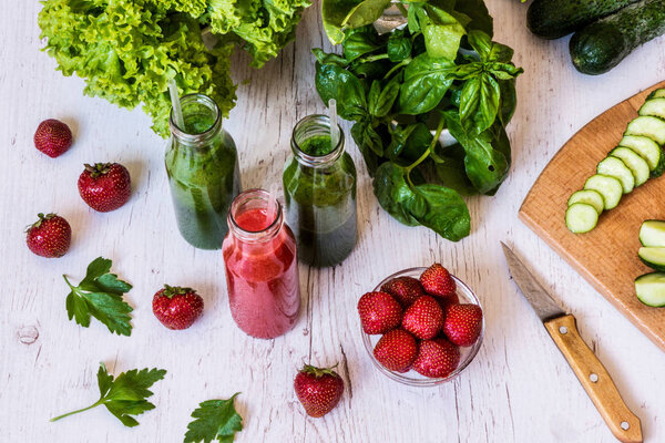 Fresh green smoothies and strawberry smoothie with ingredients on a light wooden background. Healthy detox drinks.