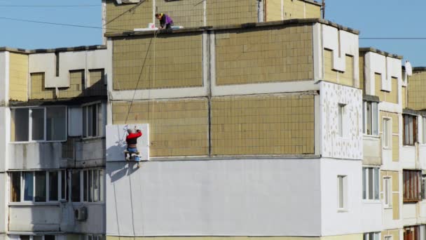 Worker man insulates wall high-rise building — Stock Video