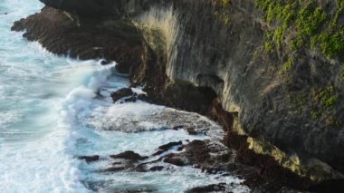 Dalgalar kayaların üzerinde sıçrama şekli oluşturan bir tropikal plaj isabet. Güçlü dalgalar kayalık bir plajda. Ünlü Uluwatu Tapınağı Bali, Endonezya.