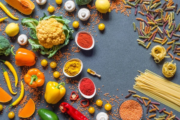 Verdure diverse, spaghetti e fettuccine, spezie. ingredienti vegani crudi sani per cucinare su sfondo grigio con spazio libero per la copia. Posa piatta, vista dall'alto . — Foto Stock