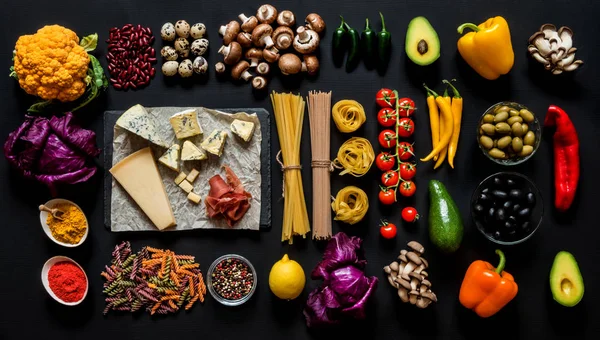 Různé čerstvé suroviny na vaření italské těstoviny, špagety, fettuccine, fusilli a zelenina na černém pozadí. Plochá ležel, horní pohled. — Stock fotografie