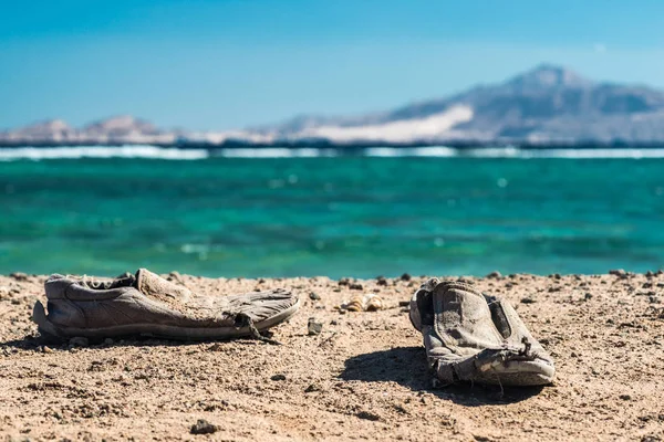 Paire de vieilles chaussures minables sur la plage de sable. Vieilles chaussures minables sur le sable . — Photo