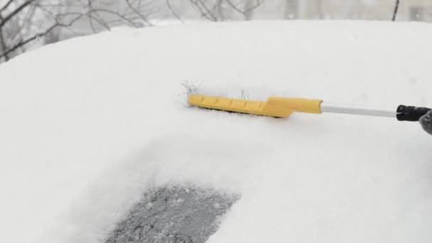 Quitar la nieve de la ventana de un coche con un cepillo. Cepillar el parabrisas de la nieve . — Vídeo de stock