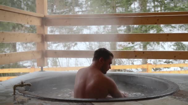 Un uomo si lava le mani e il viso nella vasca. Un uomo sta facendo il bagno nella vasca di ghisa con acqua minerale . — Video Stock