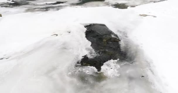 Eis schmilzt - der Fluss fließt. Blick auf einen Gebirgsfluss in den Karpaten im Winter. — Stockvideo