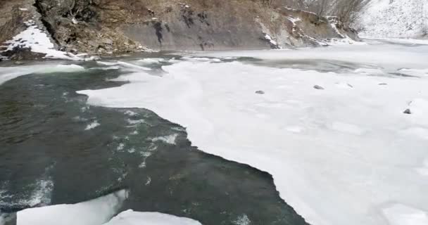 Aerial view og ice melts - the river flows. View of a mountain river in the Carpathians in winter. — Stock Video