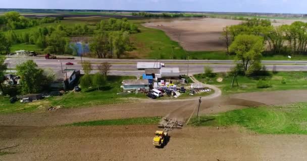 Aerial film av en traktor på ett fält nära motorvägen — Stockvideo