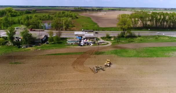 Aerial film av en traktor på ett fält nära motorvägen — Stockvideo