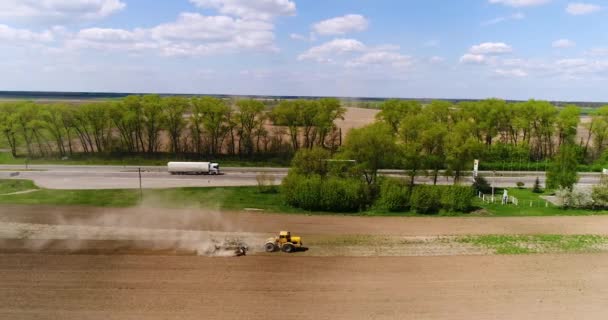 Aerial film av en traktor på ett fält nära motorvägen — Stockvideo