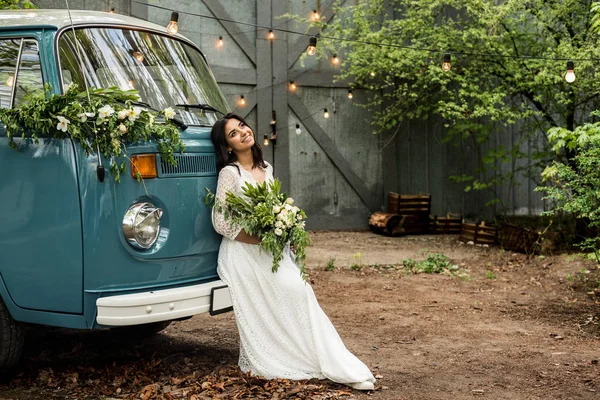 Allegro felice giovane sposa sedersi sul paraurti retro-minibus. Primo piano . — Foto Stock