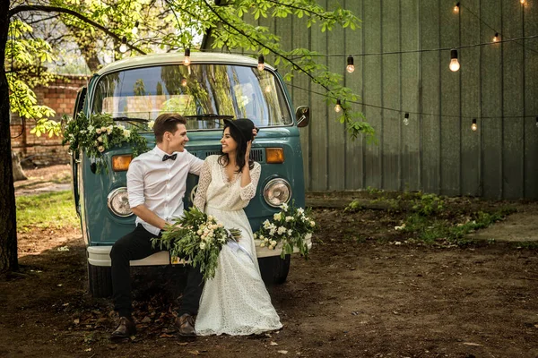 Fröhlich-fröhliches junges Paar sitzt auf dem Stoßstangen-Retro-Minibus. — Stockfoto