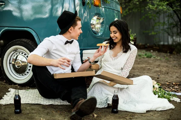 Cheerful happy young couple eat and drink near retro-minibus. Close-up.
