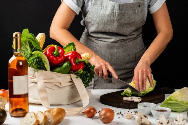 Ev mutfağı konseptinde sağlıklı yemek pişirmek. Önlüklü kadın sebze doğruyor..