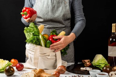 Kadın elinde farklı taze sebzeler ve kırmızı biberlerle dolu bir pamuk eko çanta tutuyor. Sağlıklı ve temiz yemek pişirmek. Sıfır atık satın alma kavramı.