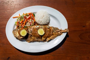 Yanında meze ve ahşap bir masada salata ile ızgara okyanus balığı..