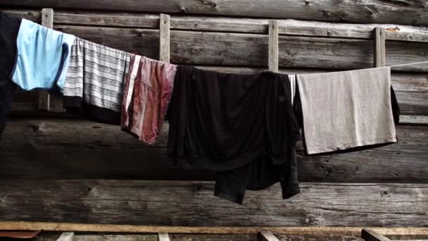 Clothes hanging on a rope on the background of a wooden house. — Stock Video